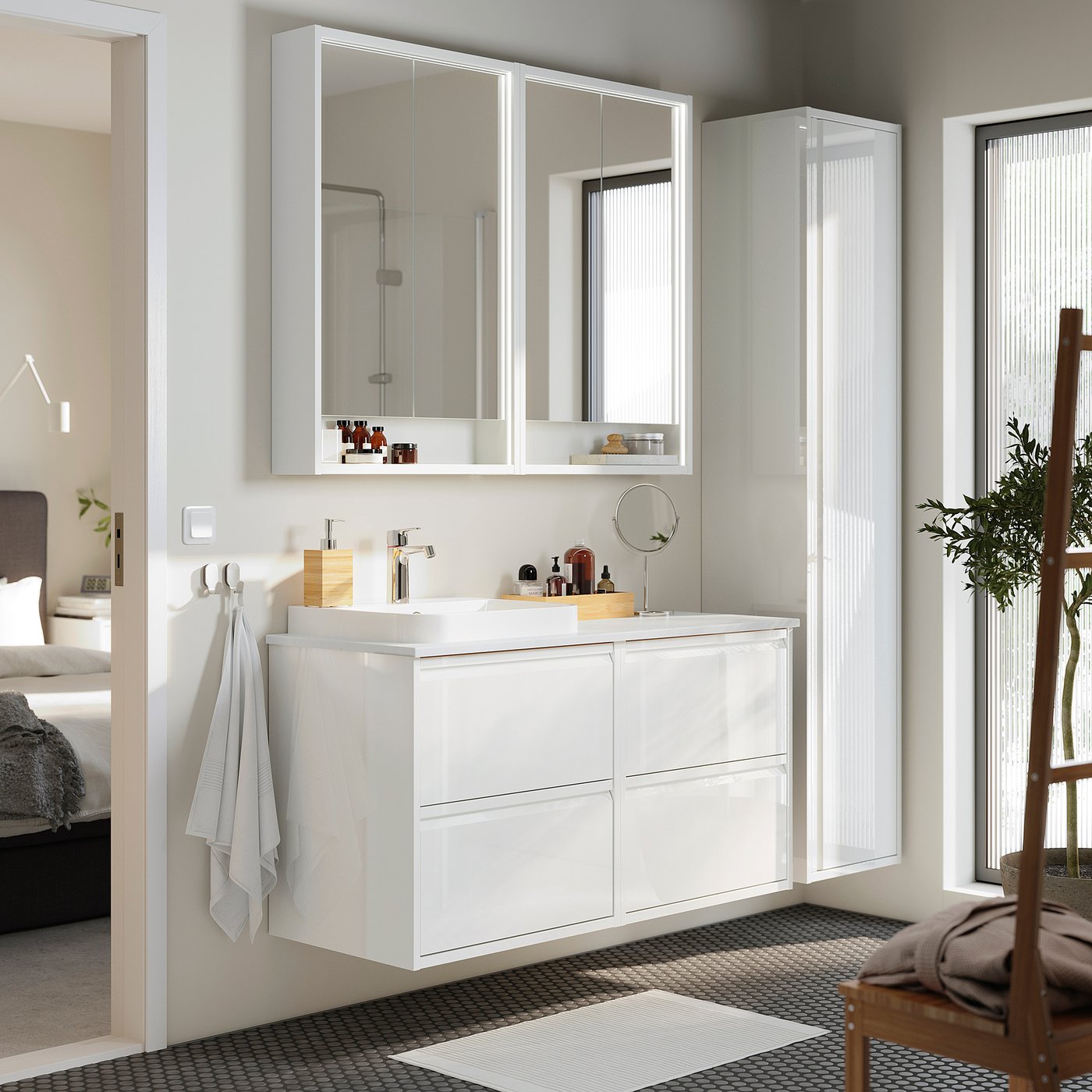 A modern white bathroom with ÄNGSJÖN units, wall cabinets, countertop, basin, high-gloss finish, and a small chair.