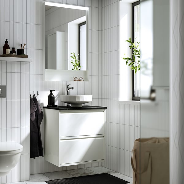 ÄNGSJÖN wash-stand, round basin, black soap dispenser, wall drawers, mirror reflecting minimalist bath decor.
