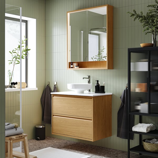 Modern bathroom with ÄNGSJÖN oak washstand, marble basin, and sage green walls.
