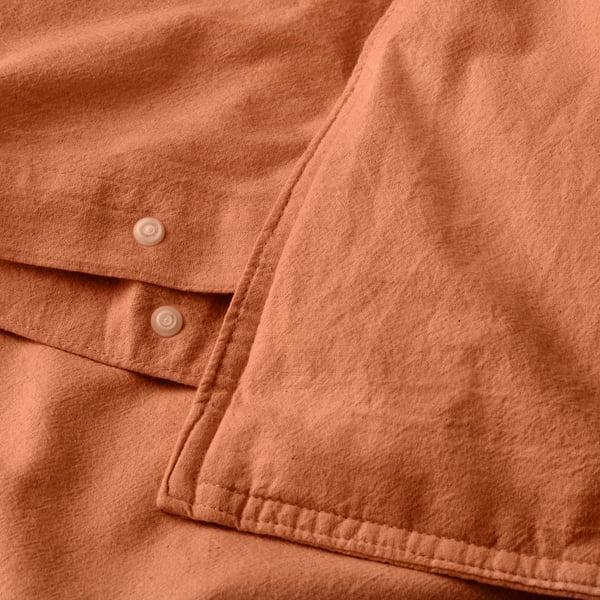 A peach-colored duvet cover set made of soft, breathable cotton with button closure at the bottom, offering a calm, cosy vibe.