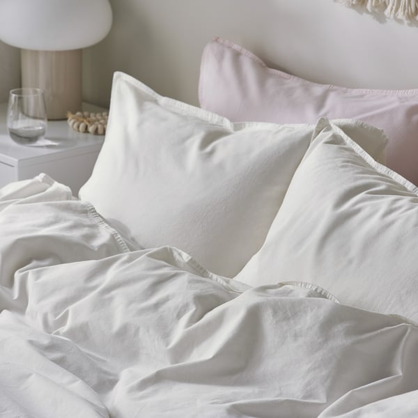 Cosy bed with smooth, white, high-quality cotton duvet and pillows. Soft, inviting, and neatly arranged with subtle details.