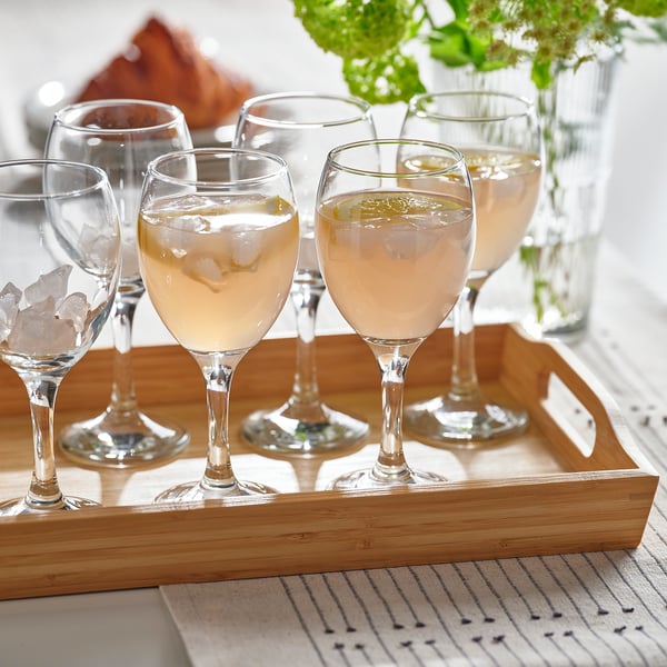 Wooden tray holding six wine glasses, some filled with clear liquid and ice, showcasing their use for beverages.