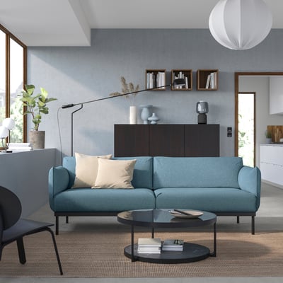 Contemporary living room with teal ÄPPLARYD sofa, black coffee table, and minimalist decor.