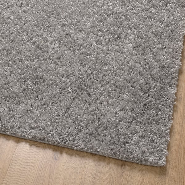 Soft, plush grey rug on wooden floor, providing comfortable, cosy texture.