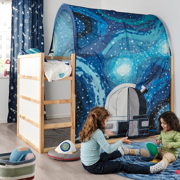 Girls playing inside glow-in-the-dark spaceship tent next to bunk bed with curtains.