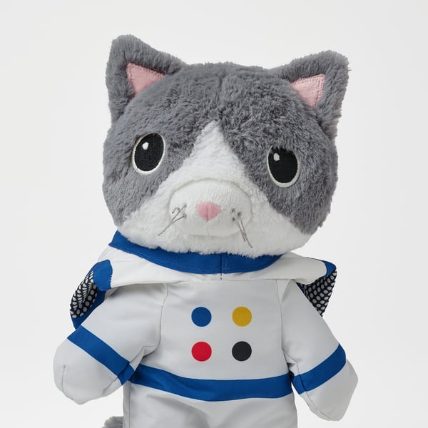 Soft grey stuffed cat in astronaut outfit, white with colourful spots, detailed high-quality fabric.