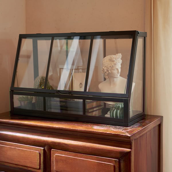 Display case with statue on wooden chest.