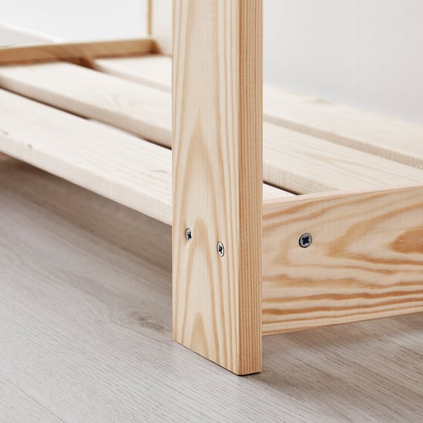 Natural wood furniture corner, detailed with screws, on a light floor.