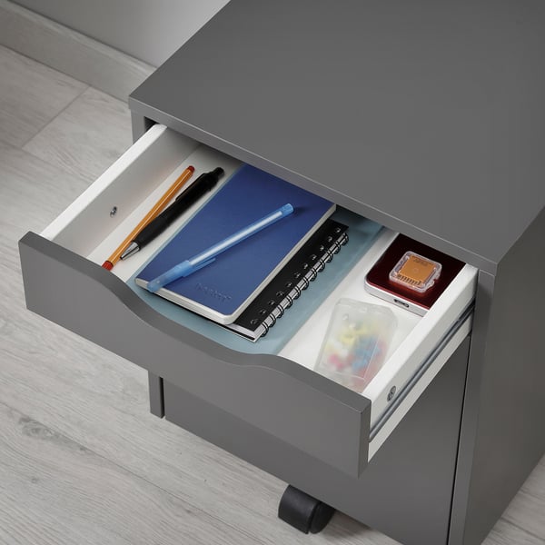 Open grey drawer unit showing pens, notebooks, and small boxes inside, ideal for storage.
