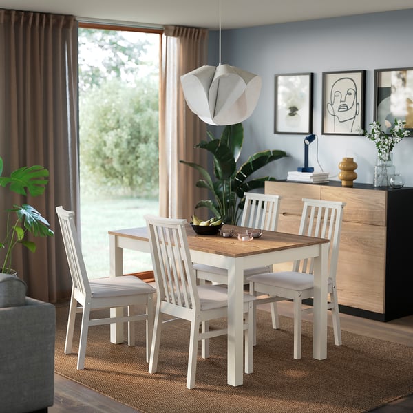 White ÅLHULT dining table with wooden top, surrounded by matching chairs in cosy dining area.