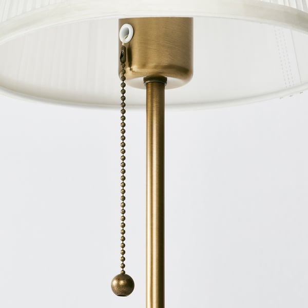 Golden lamp detail with pull chain for switch, white shade.