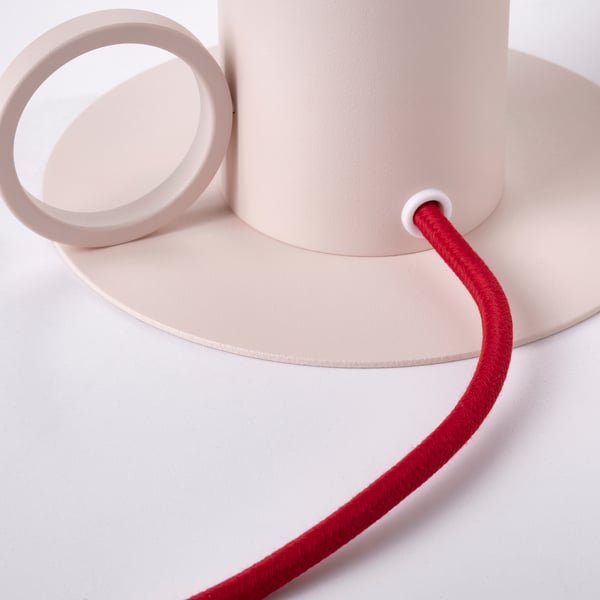 Modern lamp with smooth beige finish and red cord, showcasing sleek design and quality materials.