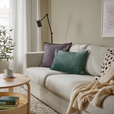 Cosy living room with green cushion sofa, books table, white walls.