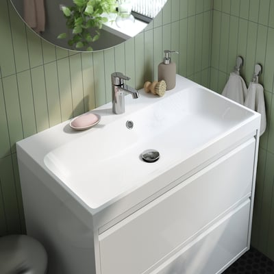 A modern bathroom sink with integrated marble basin, sleek chrome tap, and storage for soap. It fits seamlessly into a wash-stand.