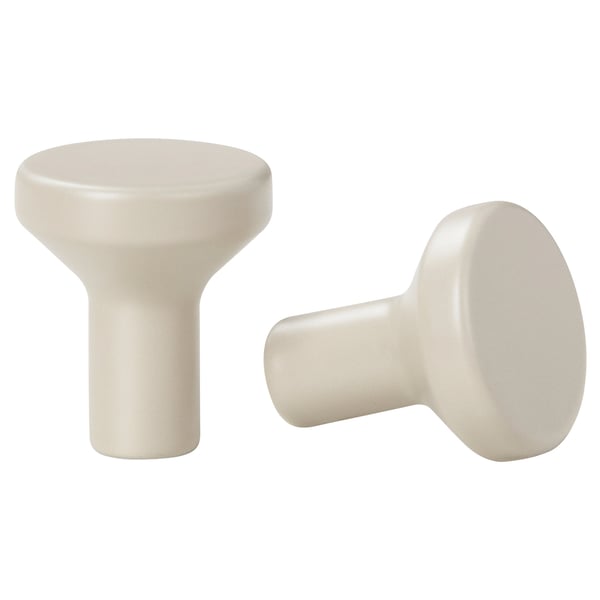 Two off-white BAGGANÄS knobs, round with a smooth finish, designed for cabinet handles, set against a white background.
