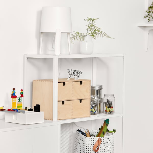 White bookshelf with toys, jars, and lamp.