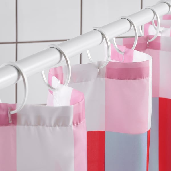 Shower curtain with colour blocks hangs from rings. Water-repellent, freshens bathroom.