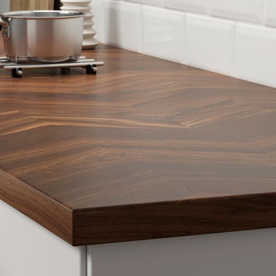 Wooden kitchen countertop with dark-rich, natural grain patterns; sits against tiled wall, promoting elegance and durability.