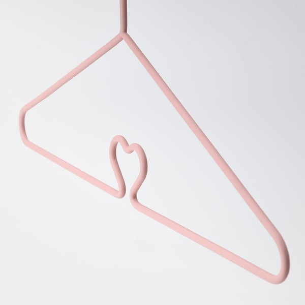 A pastel pink hanger with a heart-shaped hook, designed for childrens clothes, anti-slip surfaces and durable steel construction.