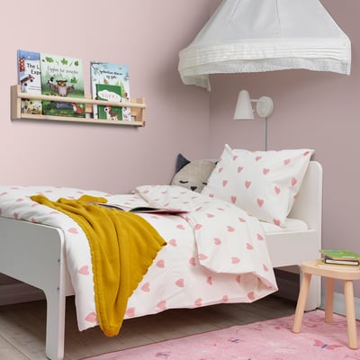 Kids room with BARNDRÖM duvet, hearts, yellow blanket, bookshelf, and stool.