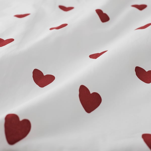 White duvet cover with scattered red hearts, soft cotton texture, inviting and cosy.