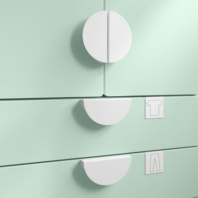 Three pastel pink, circular storage handles attached to light green surfaces.