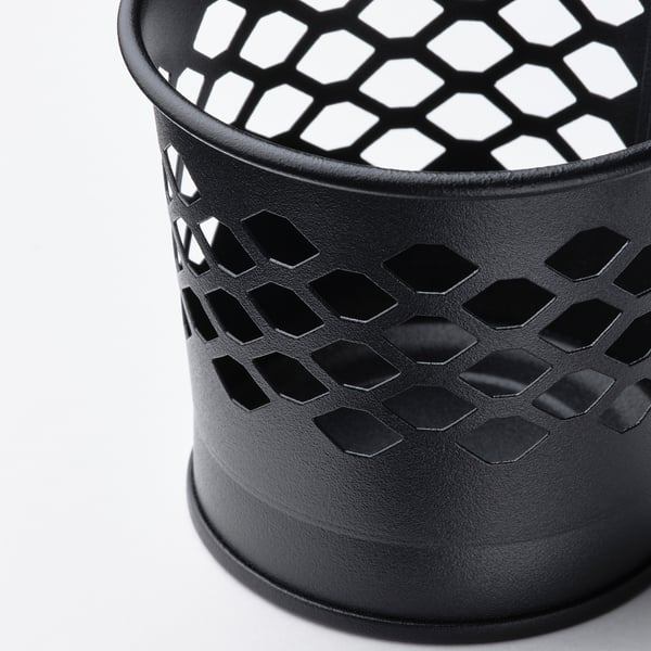 Black metallic candle holder with intricate cut-out patterns, casting delicate shadows. Clean, modern design.