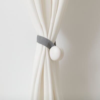 White curtains tied back with grey fabric tie featuring magnetic ends for secure holding.