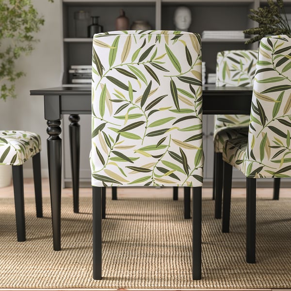 Chairs with floral covers and black legs around a dining table on a jute rug.