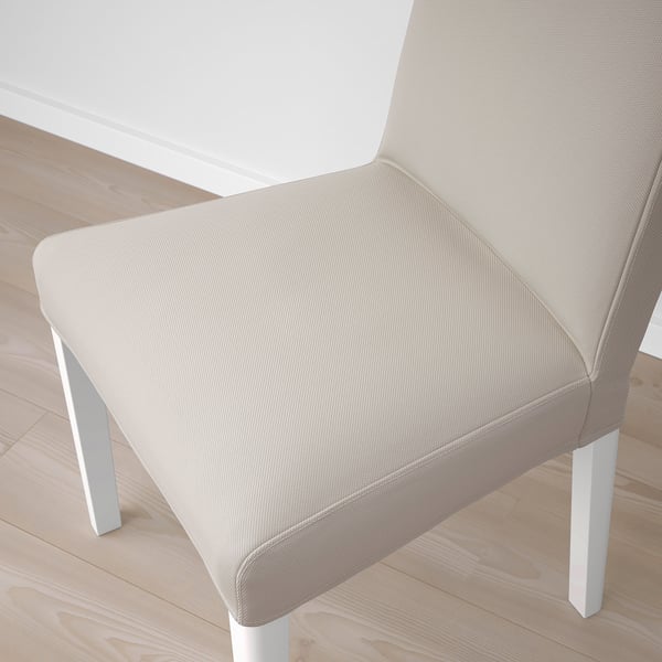 Beige upholstered chair, clean-lined modern design, placed on a wooden floor. High-quality fabric and sturdy white legs.