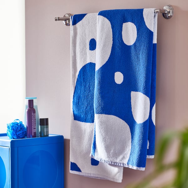 Blue & white towel with circles hangs near blue cabinet with toiletries.