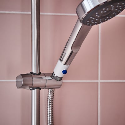 A BERGVATTNET shower booster. Its grey with a blue button, made of plastic. Cylindrical shape, designed to enhance water flow.