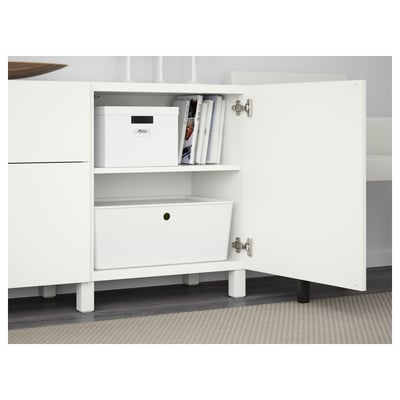 White BESTÅ cabinet with adjustable shelf holding storage boxes and books.