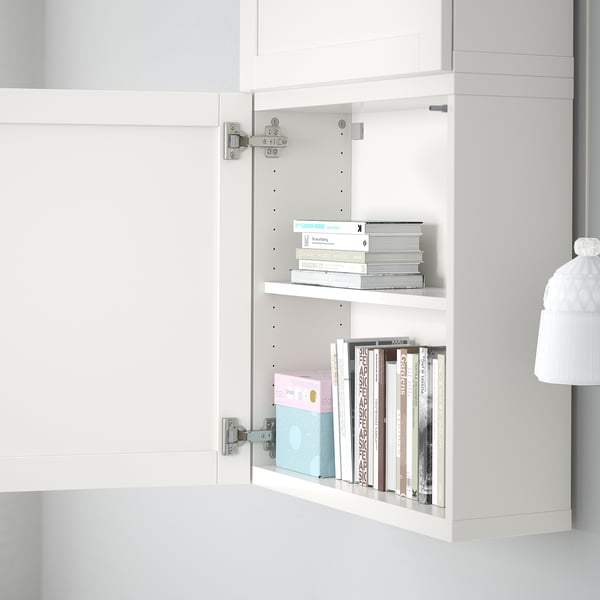 Open white cabinet with two shelves, holding stacks of books and boxes. Adjustable and customizable storage solution.