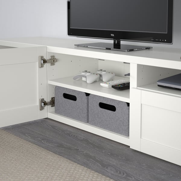 White BESTÅ tv unit with soft-close hinges, holding a tv, game controllers, and storage bins.