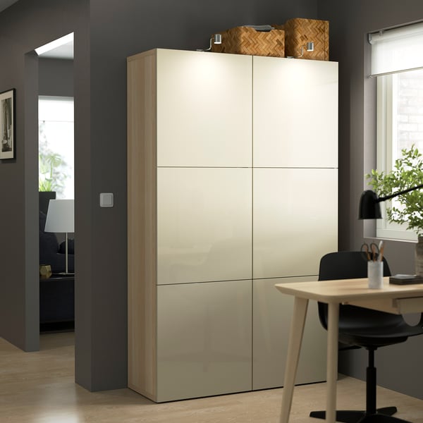 Tall BESTÅ storage with cream doors in modern office, wicker baskets.