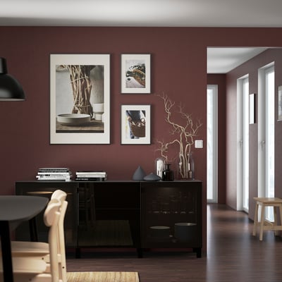 Modern living room with maroon BESTÅ sideboard, black cabinet, and art pieces.