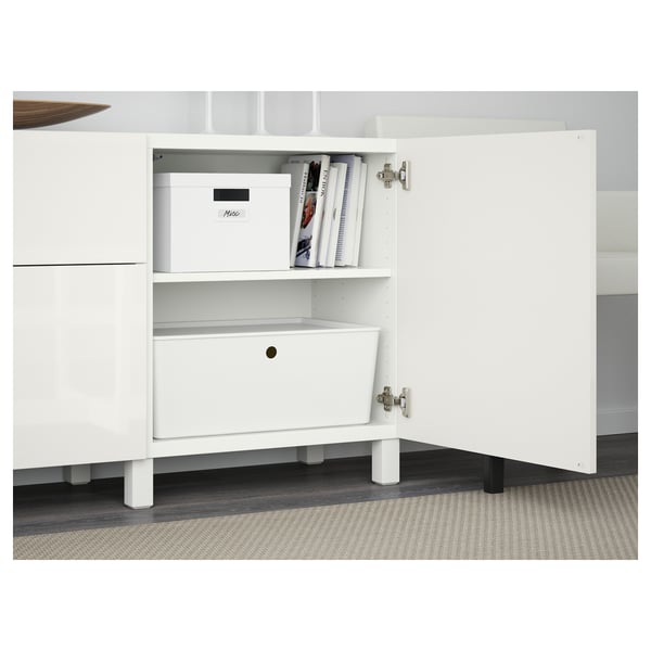 White BESTÅ sideboard with adjustable shelves, drawers, and soft-closing function. One door open, showing storage boxes and books.
