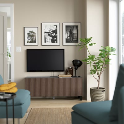 Modern living room with BESTÅ tv stand, flat-screen tv, storage cabinet, and plant. Blue-green couches with yellow pillow.