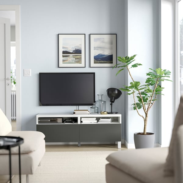 Modern living room with grey walls, green tv stand, flat-screen tv, plant, sofa, photos, decor.