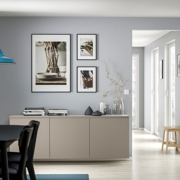 Modern living room with BESTÅ unit, vases, books, art, lamp, stool, chairs.