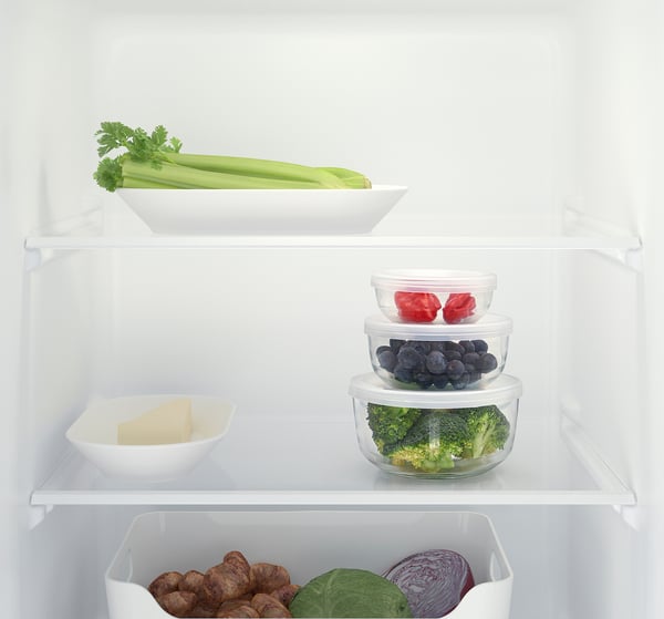 Fridge shelf with glass containers holding vegetables and leftovers, organised and stacked efficiently.