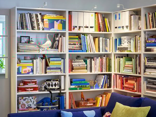 A cosy room a blue BILLY bookcase filled with colourful books and decorative items, creating a vibrant and inviting atmosphere.