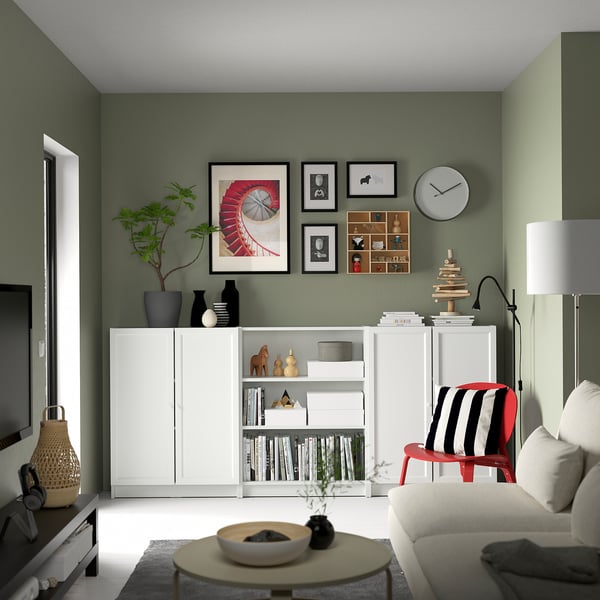 Modern living room with green walls, white BILLY bookcase, black and white decor, red chair, grey sofa, and wooden coffee table.
