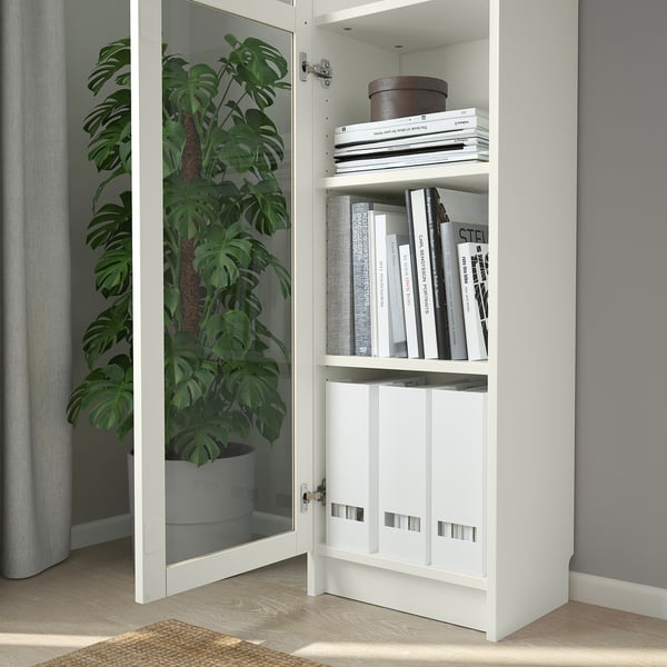 Open BILLY bookcase with glass doors displaying books and a plant, utilising wall height.