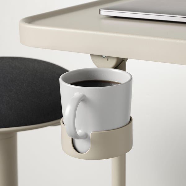 Cup holder on laptop stand securely holding white mug.