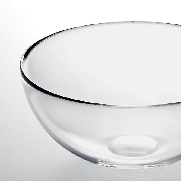 Clear glass bowl with smooth, simple design, reflecting light on edge, placed on a white surface.