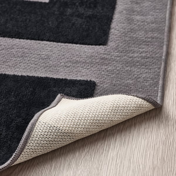 Grey rug with black patterns, soft and comfy, anti-slip backing for safety.