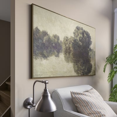 Monets large wall painting of trees, above couch with pillow, beside wall light.