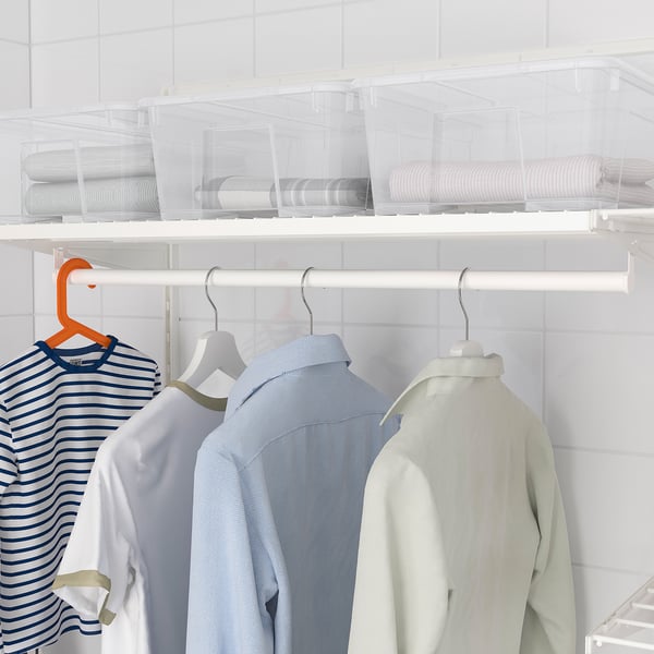 Neatly organised closet with hanging rod and storage bins for laundry.